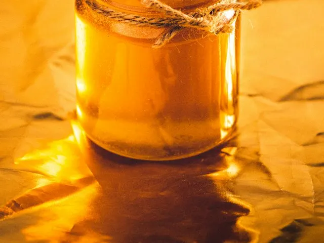 A jar of golden honey with a wooden dipper