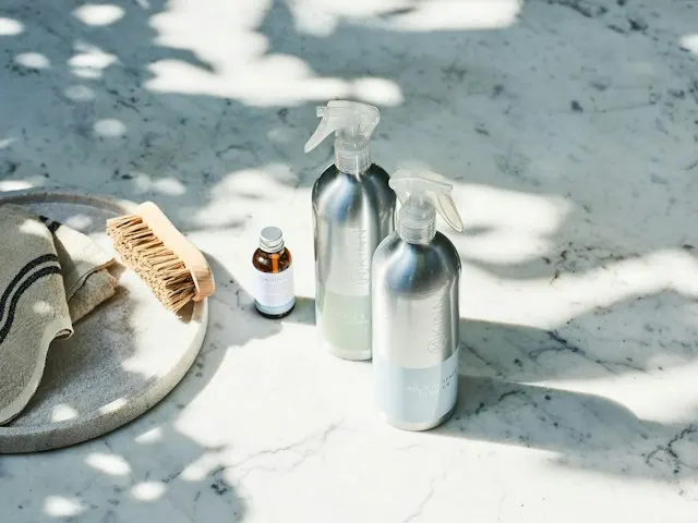 Metal and glass cleaning spray bottles in soft sunlight