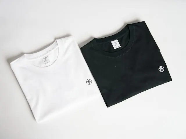 A white and a black cotton tee laid flat side by side